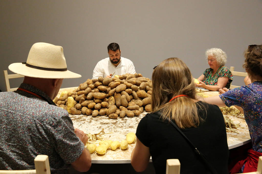 people sat around a table peeling potatoes as part of an immersive art experience