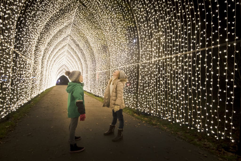 two children under the arches of the christmas cathedral at the kew christmas trail