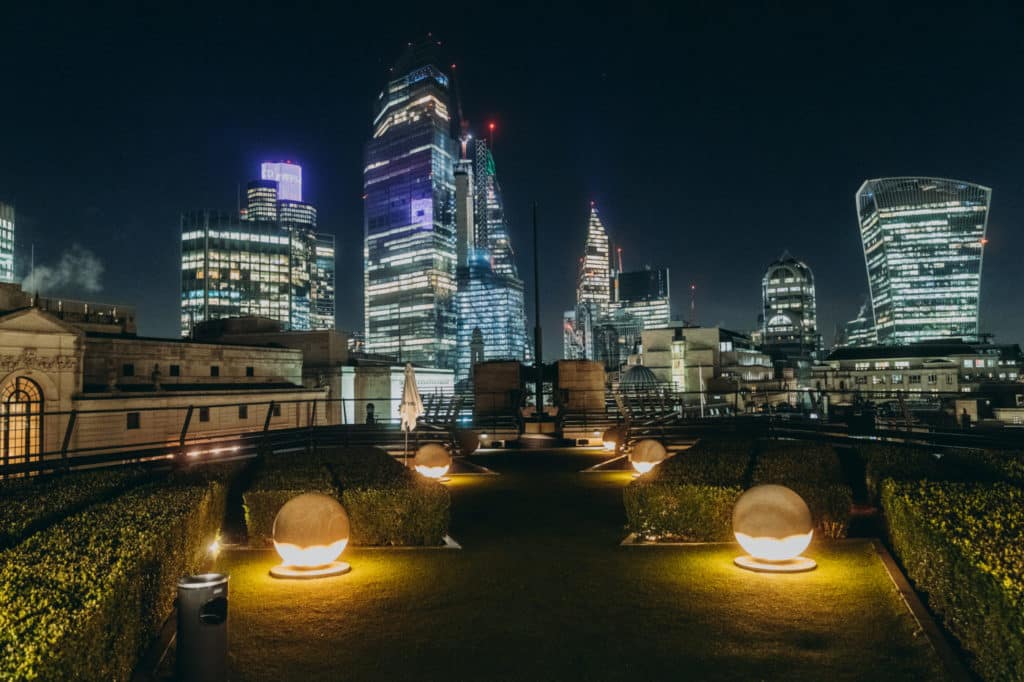 A night-time shot of london's skyline from the point of view of coq d'argent's rooftop garden