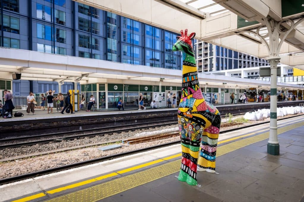 a colourful giraffe sculpture on a train platform