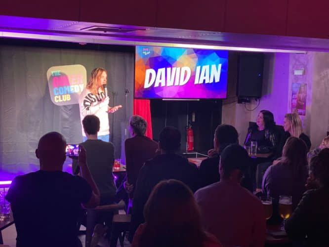 David Ian performing at a stand-up comedy club, one of the best things to do for a hen do in London