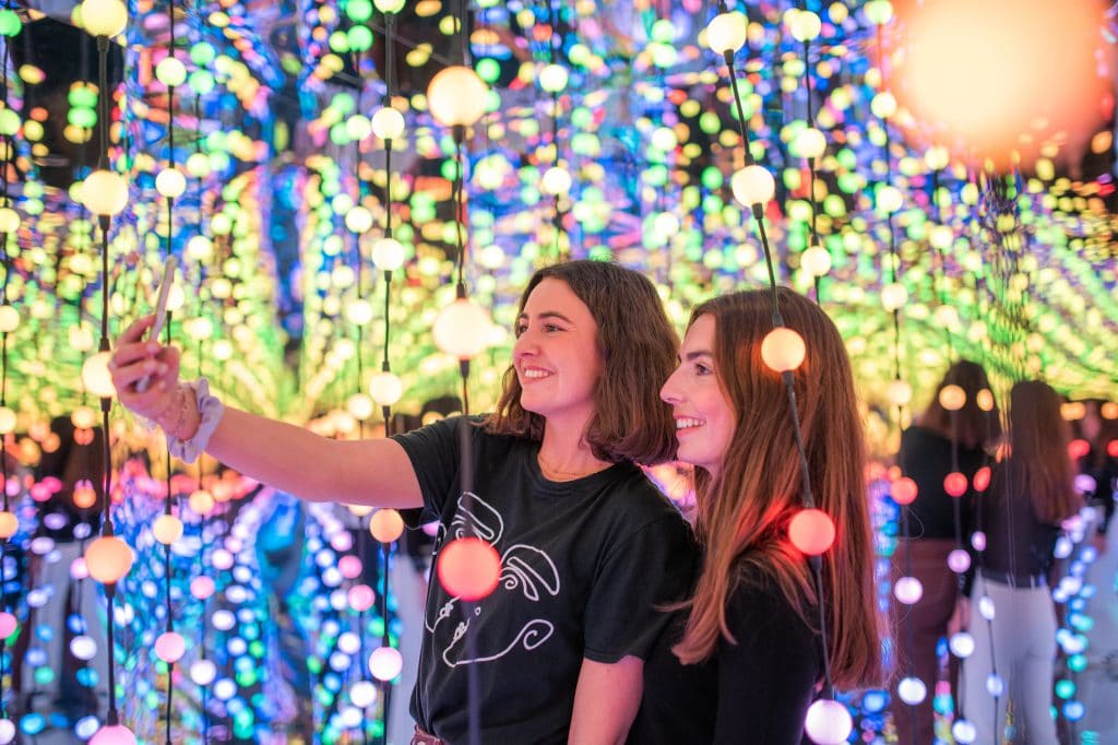 Two women posing for a photograph surrounded by lights at Dopamine Land in West Kensington, one of London's best immersive experiences 