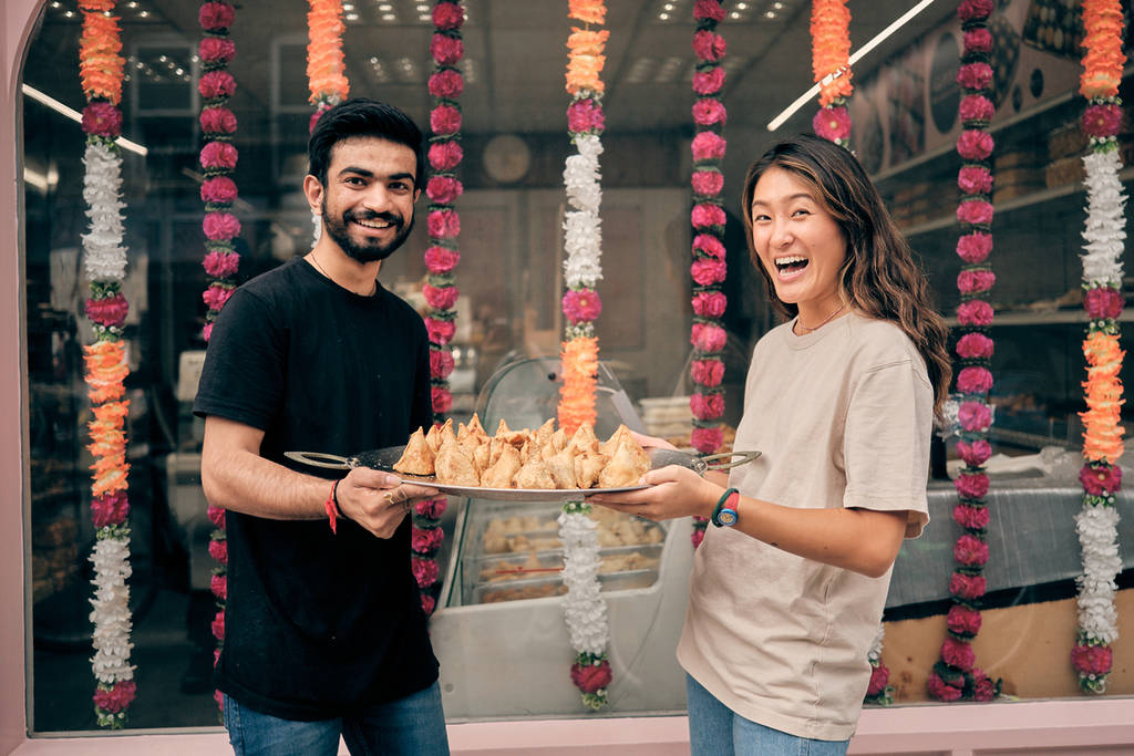 two people holding a tray laden with samosas