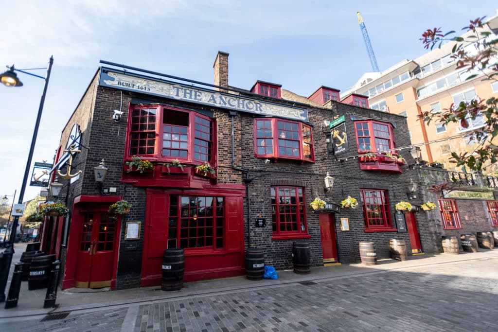 the exterior of the anchor pub in bankside, with red window frames and dark brick walls