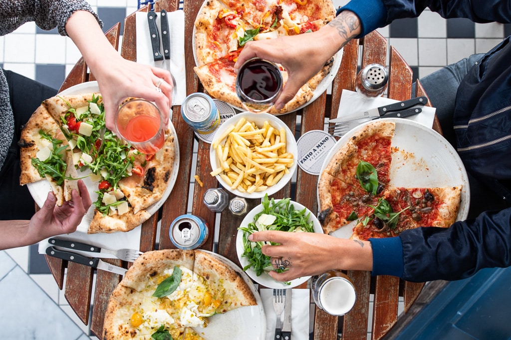 a selection of pizzas and drinks on a table, with some fries and a salad also visible