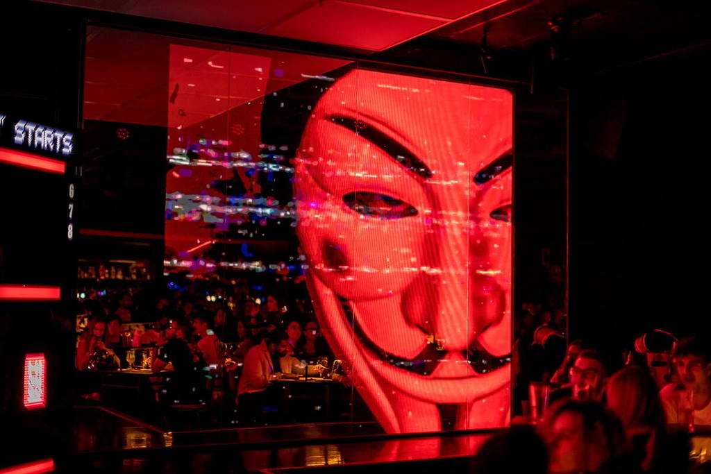 a figure wearing a guy fawkes mask on a screen at a halloween experience