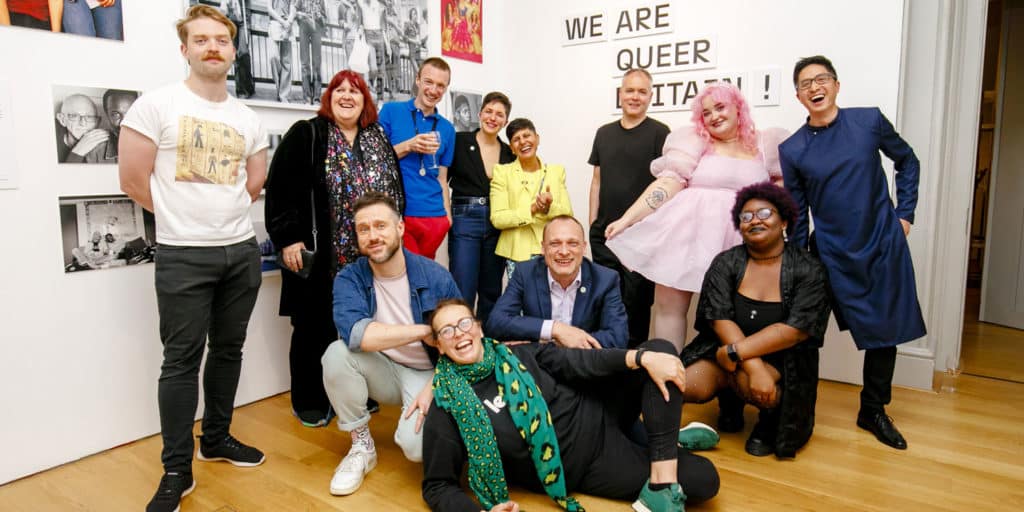 a number of people hanging out in one of the rooms of the queer britain museum