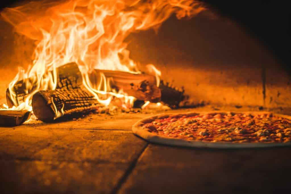 a pizza cooking in a wood burning oven at homeslice, one of London's best pizza places