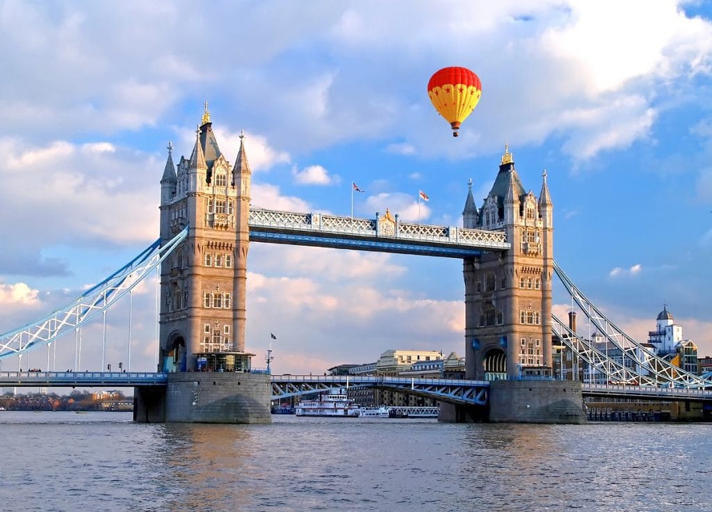 A hot air balloon approaching Tower Bridge on a bright, sunny, blue-sky day