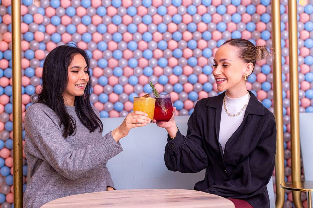 two friends cheersing their colourful mocktail drinks