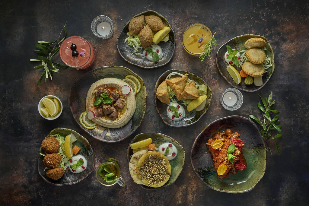 a selection of hot and cold mezzeh dishes presented in dark, earth coloured plates