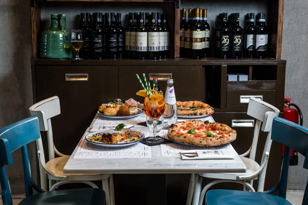 a table with pizzas, drinks, and appetizers presented on it