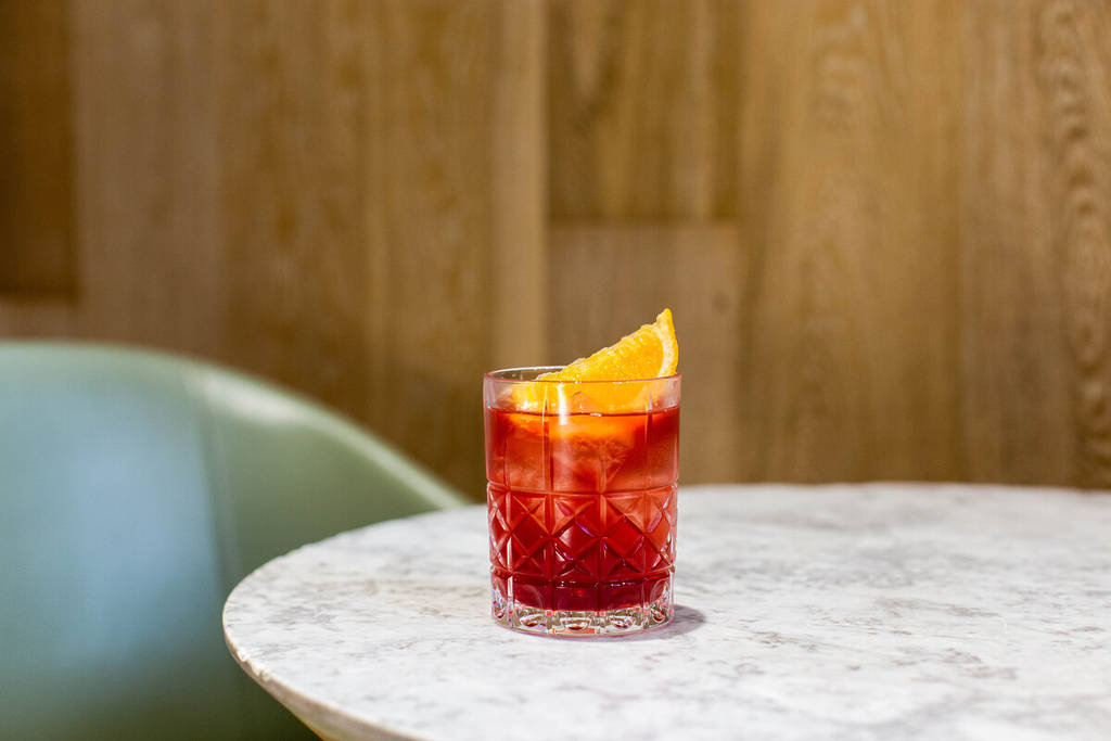 a negroni with a wedge of orange atop a marble table
