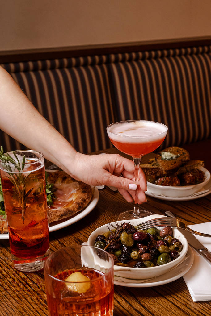 a selection of italian dishes with negroni cocktails placed around them