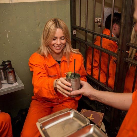 A lady enjoying a drink in the prison-themed bar Alcotraz in London