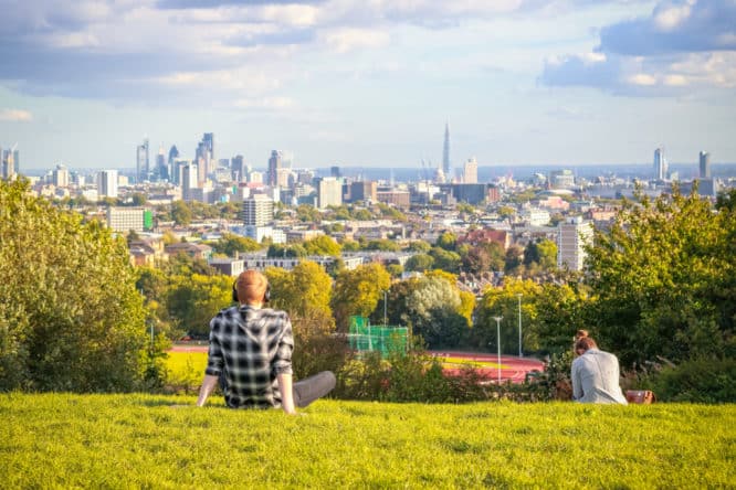 Someone sitting and enjoying the view from the summit of Parliament Hill in North London, one of the best things to do in Highgate 