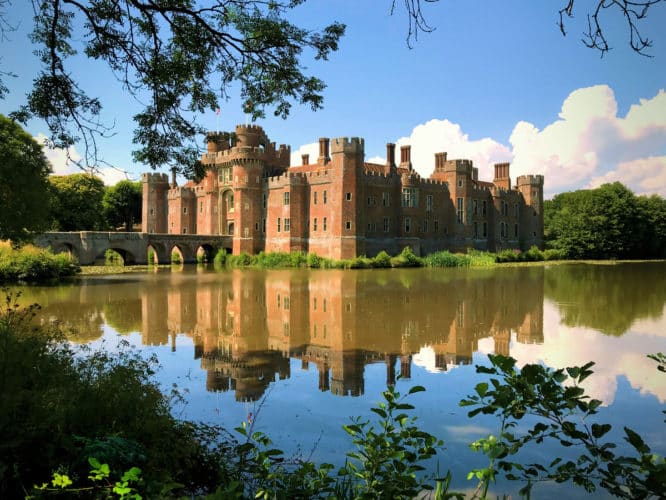 The stunning moat and blue skies surrounding the imposing. Herstmonceux Castle in East Sussex