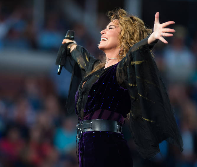 The legendary country singer and superstar Shania Twain performing to a crowd of people at a gig 