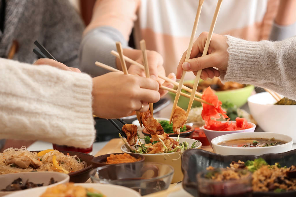 A delicious spread of Chinese food being eaten by a group of friends in London