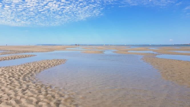 An expansive beach and bright blue skies at West Wittering in West Sussex, England