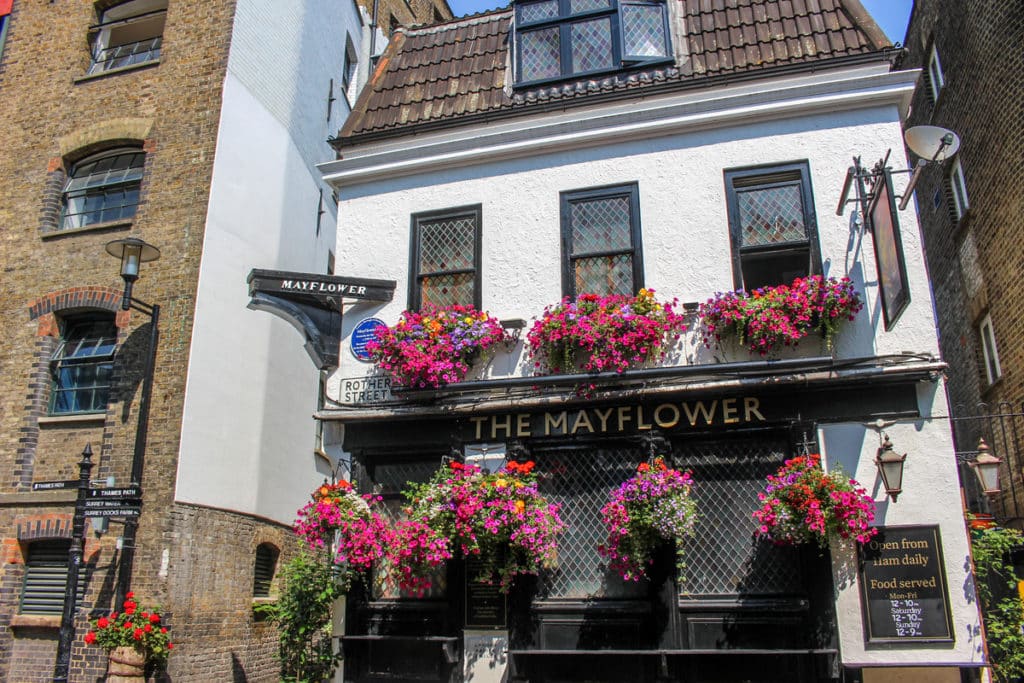 the mayflower pub, an historic white fronted pub with colourful flowerpots hanging from the front