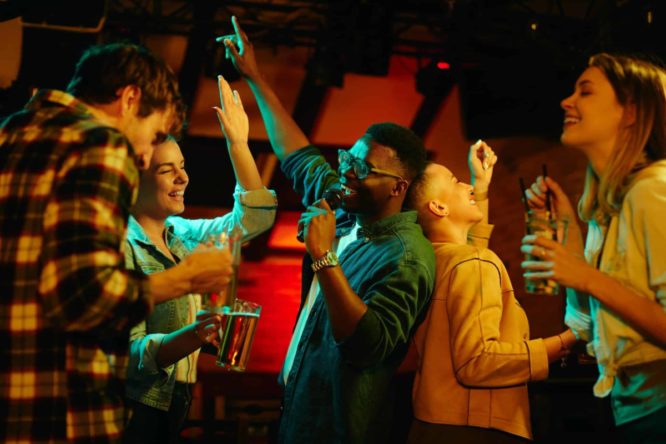 group of young people singing karaoke in a bar 