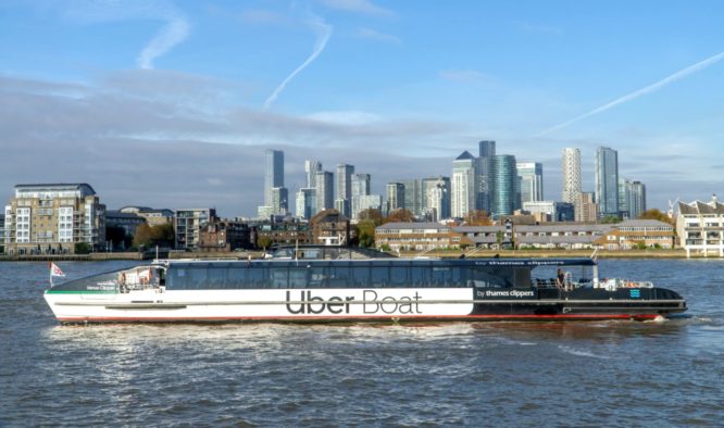 An Uber boat on the Thames, with London's skyline in the background