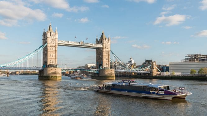 An Uber Boat making its way down the River Thames passing Tower Bridge 