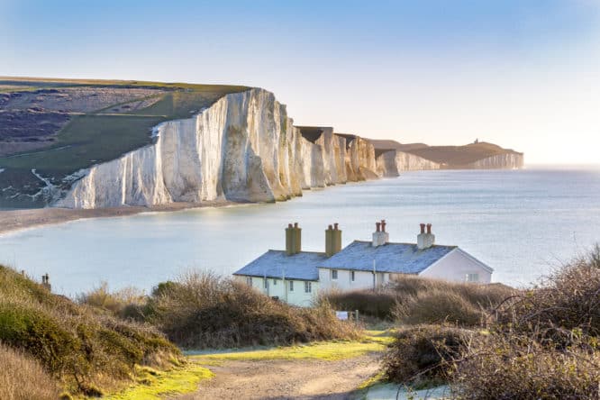 The famous white cliffs of the Seven Sisters with cottages in front of it in Sussex, England