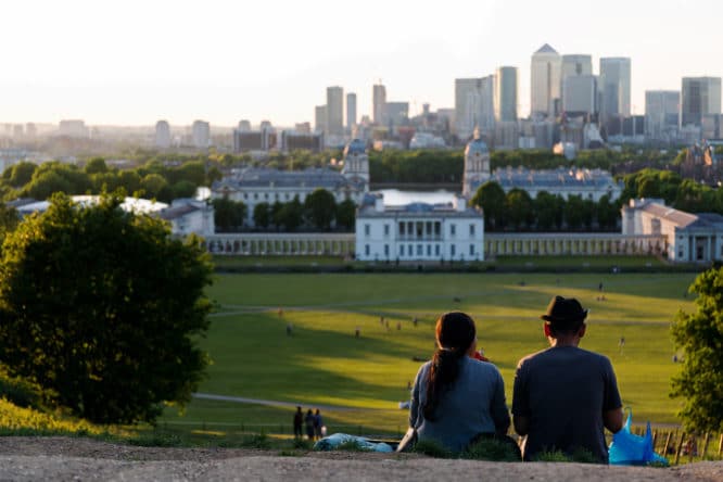 A couple enjoying a picnic at Greenwich Park in London, one of the best date spots in London