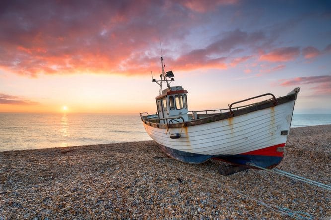 A boat on Dungeness Beach at sunset in Kent, England