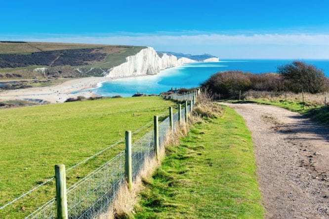 The towering cliffs and green fields of Cuckmere Have, one of the best hidden beaches near London 