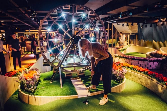 A lady playing crazy golf at the Swingers City branch in Central London