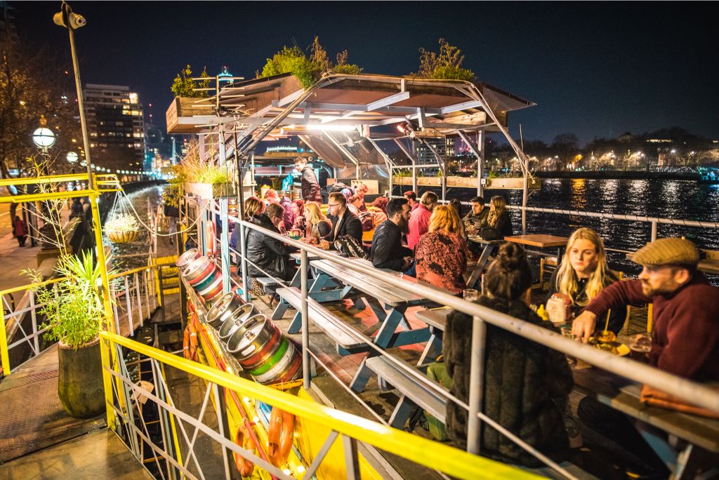 people enjoying drinks aboard the tamesis dock at night