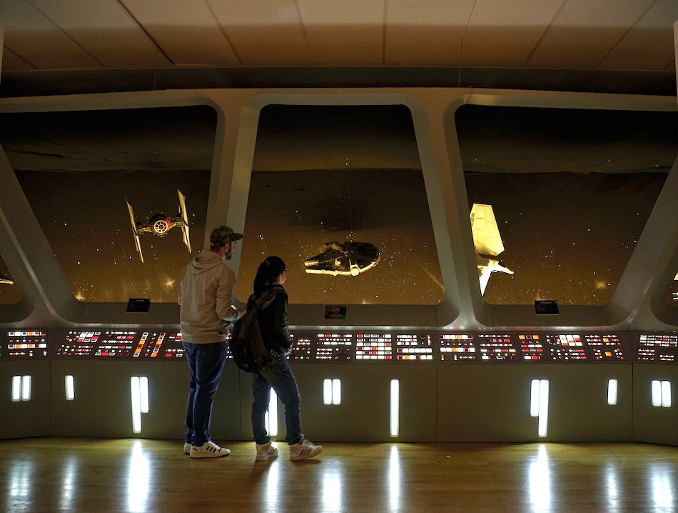 people looking out at starships in a replica set of the star destroyer deck from Star Wars