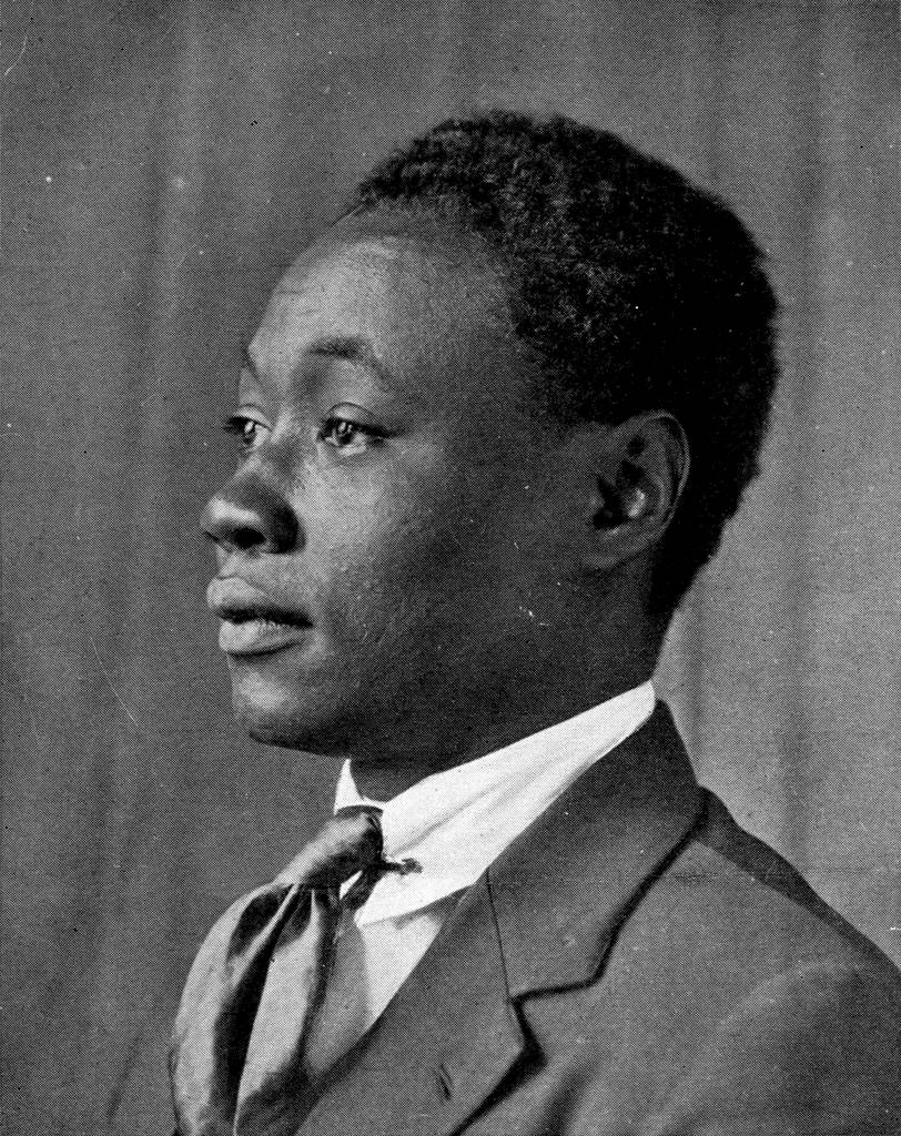 a black and white photo of a young black man in a suit looking off camera