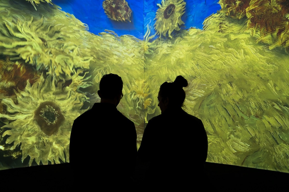 Two people watch the sunflowers bloom at London's immersive Van Gogh exhibition. Instagrammable Places In London