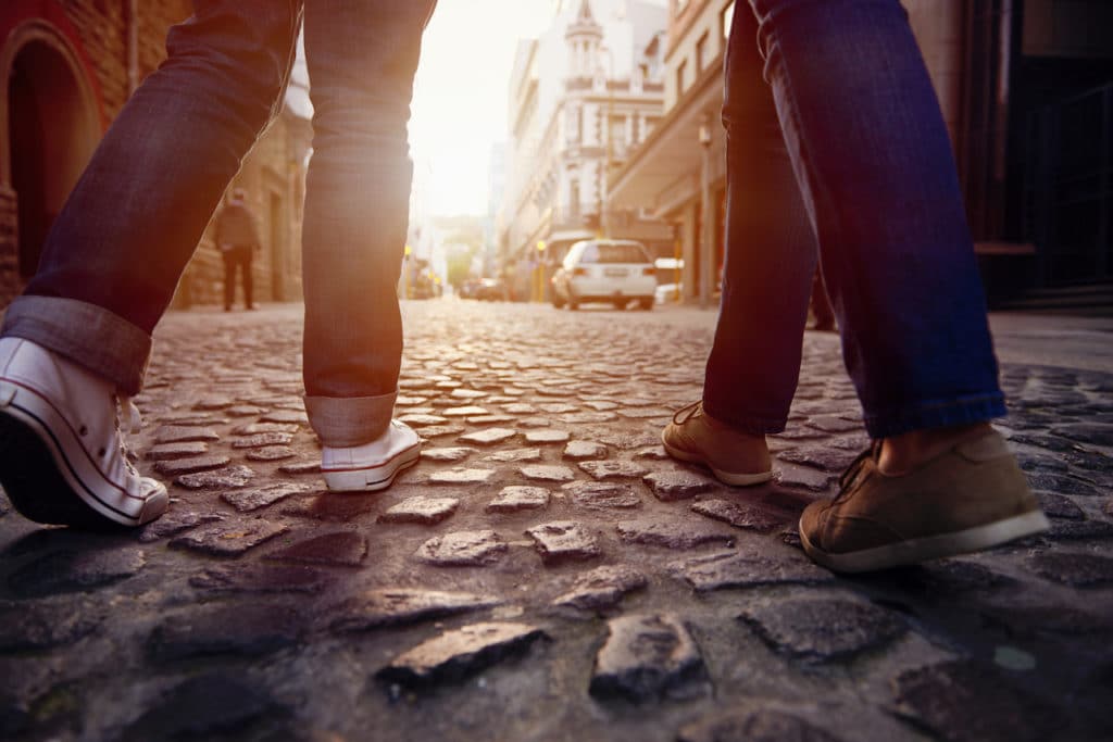 two people walking on cobblestones