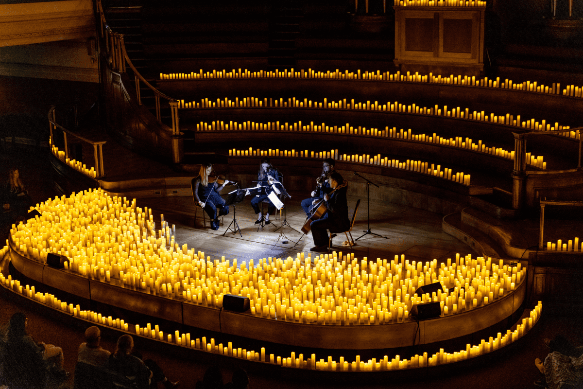 A string quartet performing at Central Hall Westminster on a stage decorated by hundreds of candles.