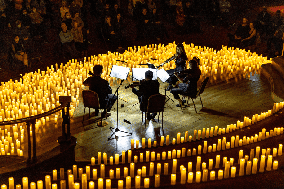 A string quartet performing on stage surrounded by hundreds of candles at Central Hall Westminster.