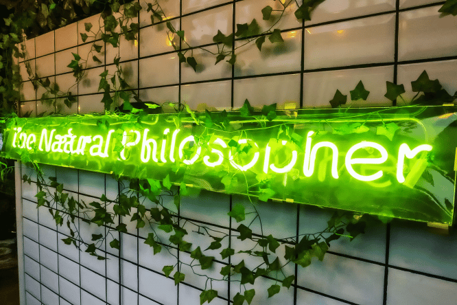 A green neon sign reading The Natural Philosopher in Hackney, London