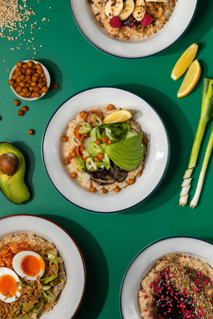an assortment of savoury oat bowls shot from above, presented on a dark green table